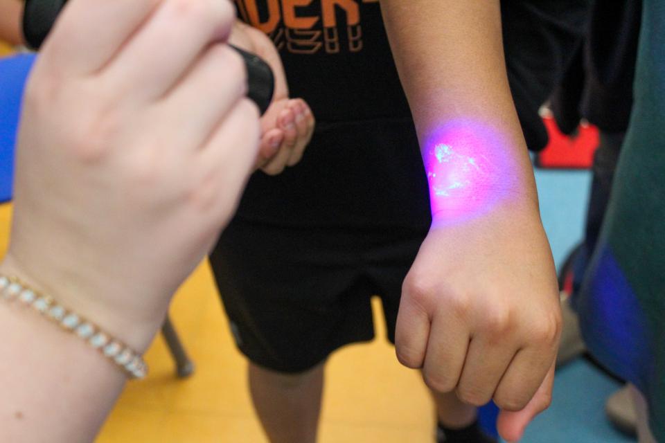 During training, students learned how to safely remove gloves that were covered in “germs”. Then, they used a special light to determine if they had stayed clean during the process. Looks like this student needs a bit more practice!