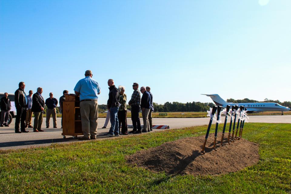 A jet briefly interrupts the ceremony, roaring to life on the nearby runway as it prepares for take-off.