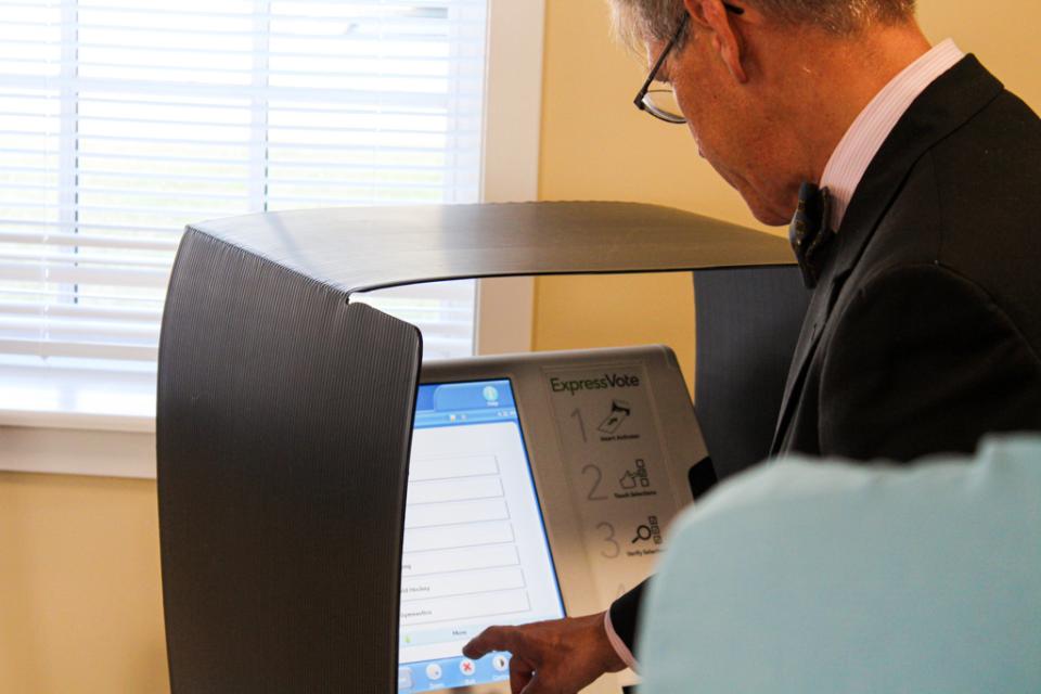 Council Vice President Pete Lesher tries the Express Vote machine, voting on his favorite Maryland symbol before printing his completed ballot and placing it in the voting counter machine.